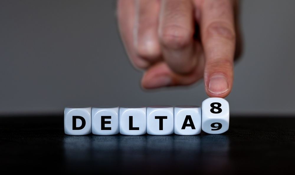 die with letters spelling out delta8 with a finger flipping 1 dice from the number 8 to 9