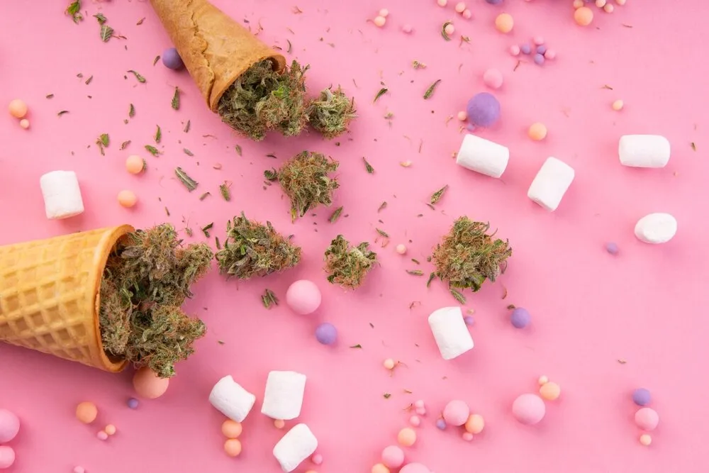 ice cream cones with bud inside surrounded by marshmallows and sweets on a pink background