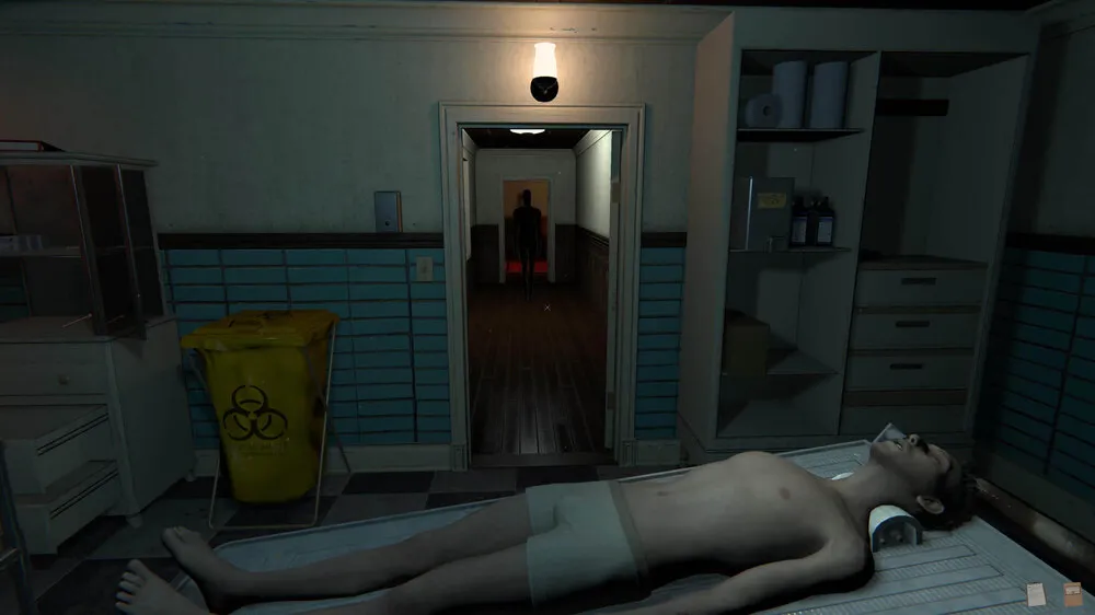 an in-game shot of the mortuary assistant with one of the bodies you are embalming on a table with a demon in the hallway watching over you