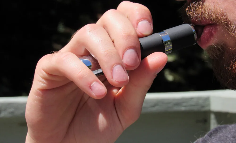 a man smoking a black thc vape