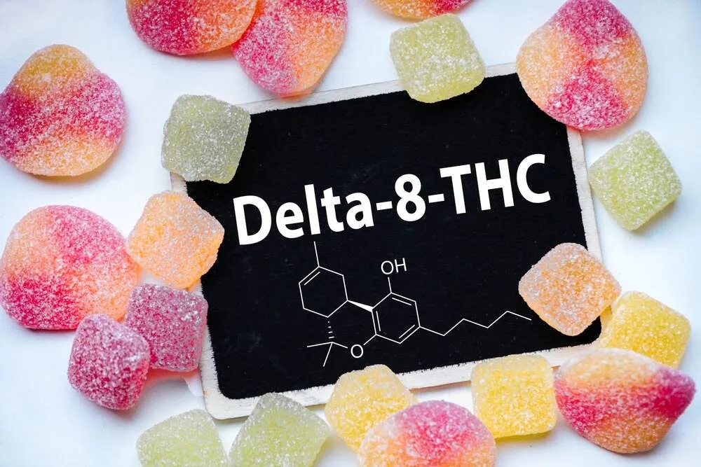 the chemical delta 8 thc on a chalk board surrounded with gummy edibles