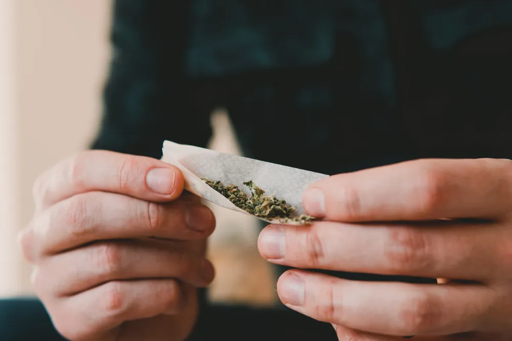 a man rolling a joint with a small amount of weed in it