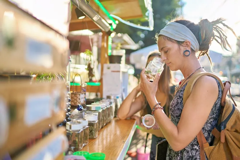 a lady at a cannabis dispensary smelling a jar of weed with a friend next to her